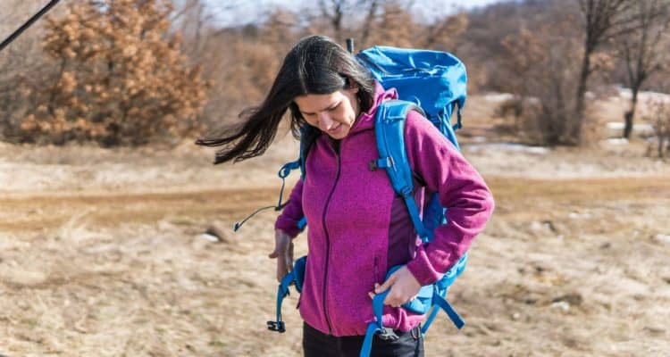 woman putting on a backpack